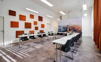 U-förmig bestuhlter Tagungsraum mit Tischen der Fürther Tourist-Information, Wandbild zeigt Rathaus