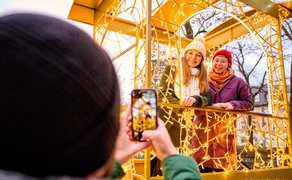 Zwei Freundinnen lachen in der goldenen leuchtenden Lok am Fürther Weihnachtsmarkt, Mann fotografiert.