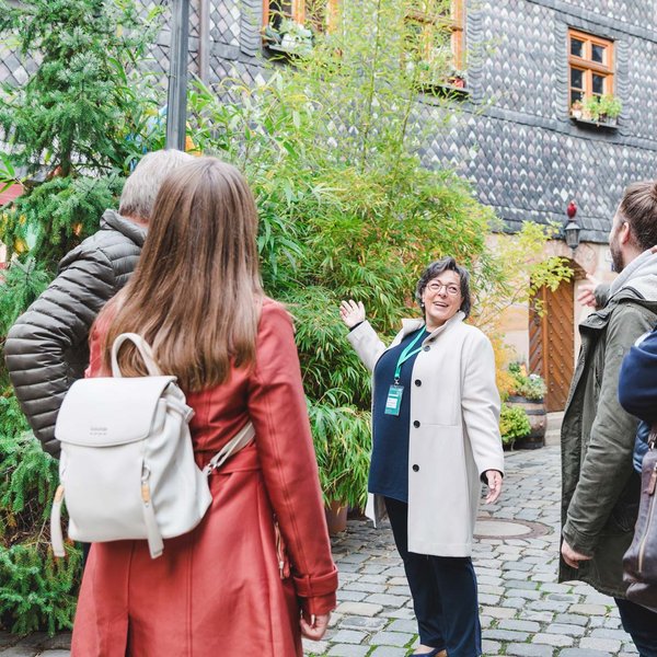 Gruppe lauscht einer Stadtführerin in einem historischen Altstadthof in Fürth während einer Führung.