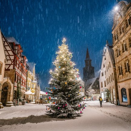Grüner Markt in Fürth im dichten Schneefall, zentral steht ein hell geschmückter Weihnachtsbaum