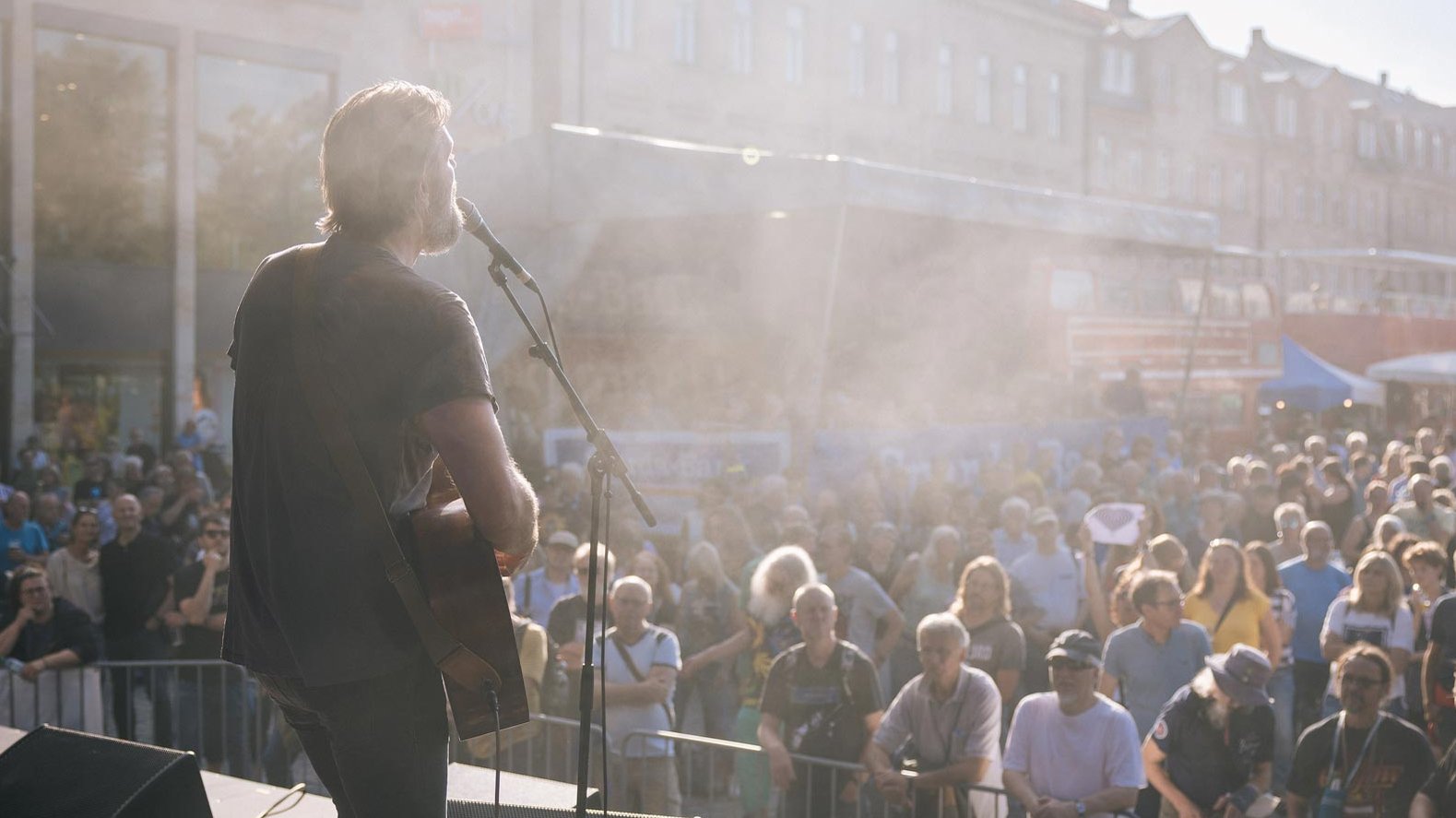 Besucher genießen Live-Auftritt eines Gitarrensängers auf der Bühne beim New Orleans Festival.