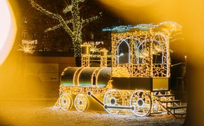 Leuchtende goldene Lok mit Lichterketten auf dem Fürther Weihnachtsmarkt, festliches Fotomotiv.