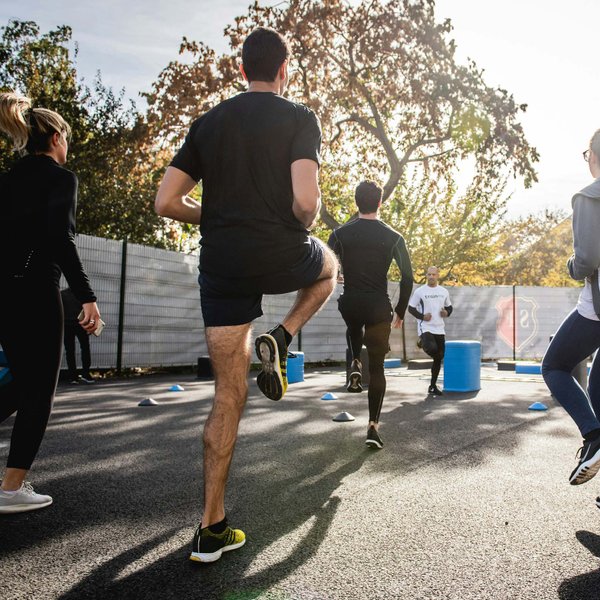 Gruppe trainiert draußen im Sonnenschein mit Beinübungen, motiviert und aktiv beim Sport.