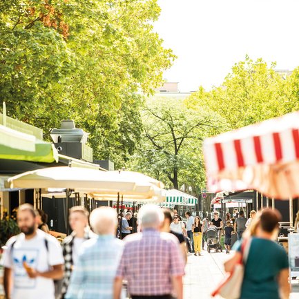 Besucher genießen einen sonnigen Tag auf dem Fürther Markt mit bunten Ständen und Menschen