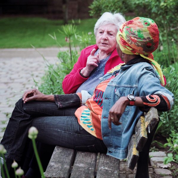 Felicia und eine ältere Dame sitzen auf einer Bank im Fürther Stadtpark und unterhalten sich herzlich.