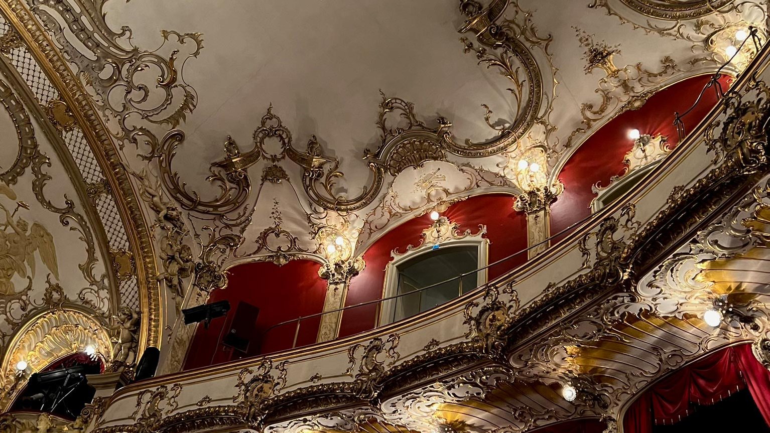 Neurokoko-Empore und Decke im Stadttheater Fürth mit goldenen Verzierungen, roten Akzenten und weißem Grund.