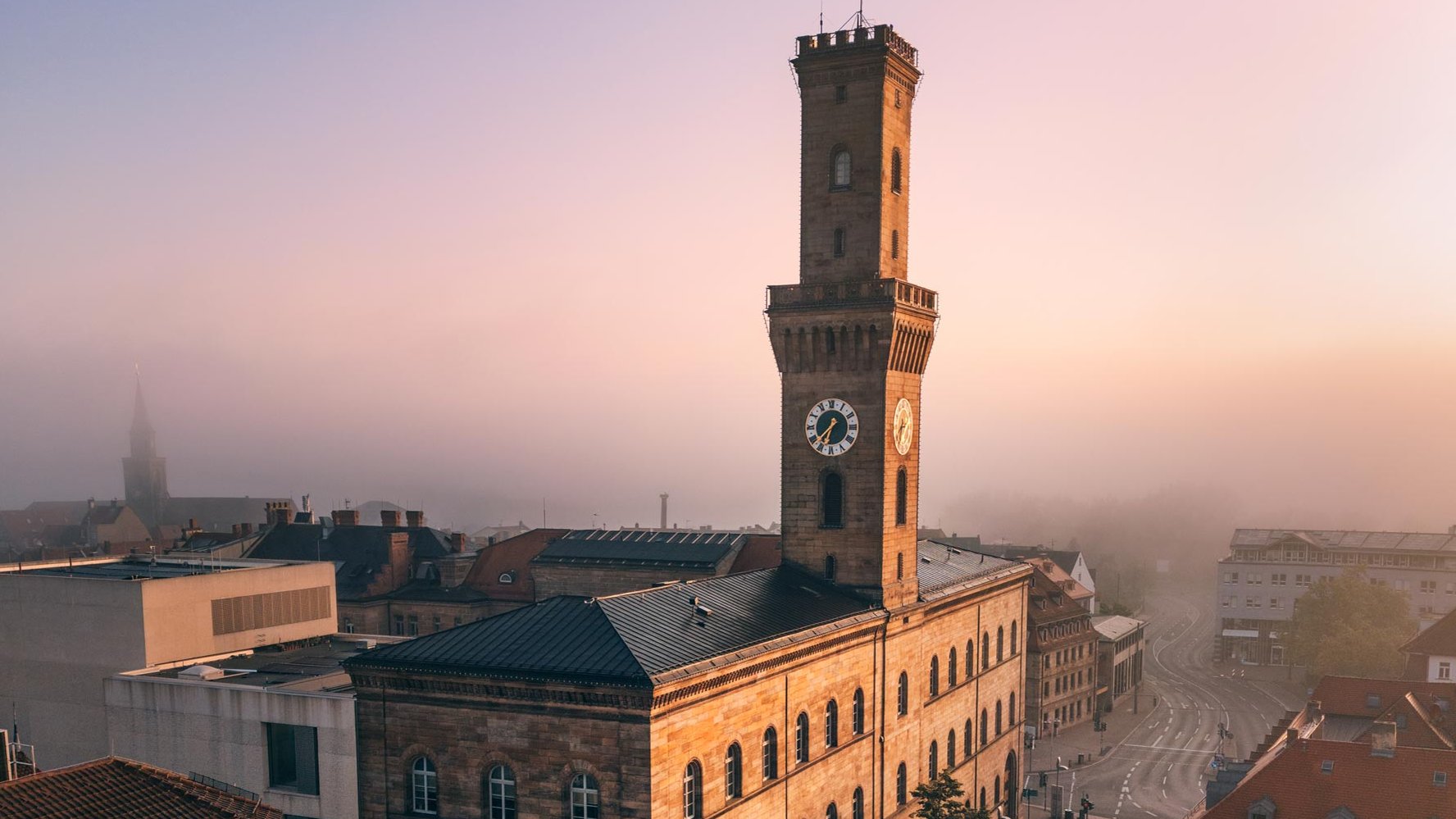Das Rathaus Fürth strahlt im Morgenlicht, während der Nebel die dahinterliegenden Gebäude verhüllt.