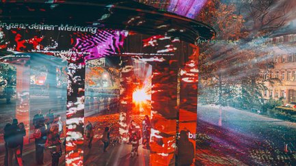 Steinpavillon auf der Konrad-Adenauer-Anlage bei Glanzlichtern, farbig beleuchtet, Besucher schauen zu.