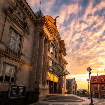 Die Abendsonne setzt den beleuchteten Eingang des Stadttheaters Fürth warm in Szene und betont die Fassade.