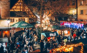 Weihnachtlich beleuchtete Stände der Altstadtweihnacht am Waagplatz, zwischen denen Besucher gemütlich schlendern.