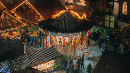 Blick auf den Weihnachtsmarkt der Fürther Freiheit mit Holzbuden, Karussell und festlicher Beleuchtung