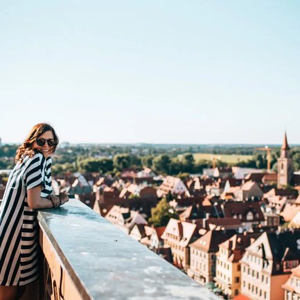 Eine junge Frau genießt auf dem Rathausturm den Panoramablick über die sonnige Fürther Altstadt