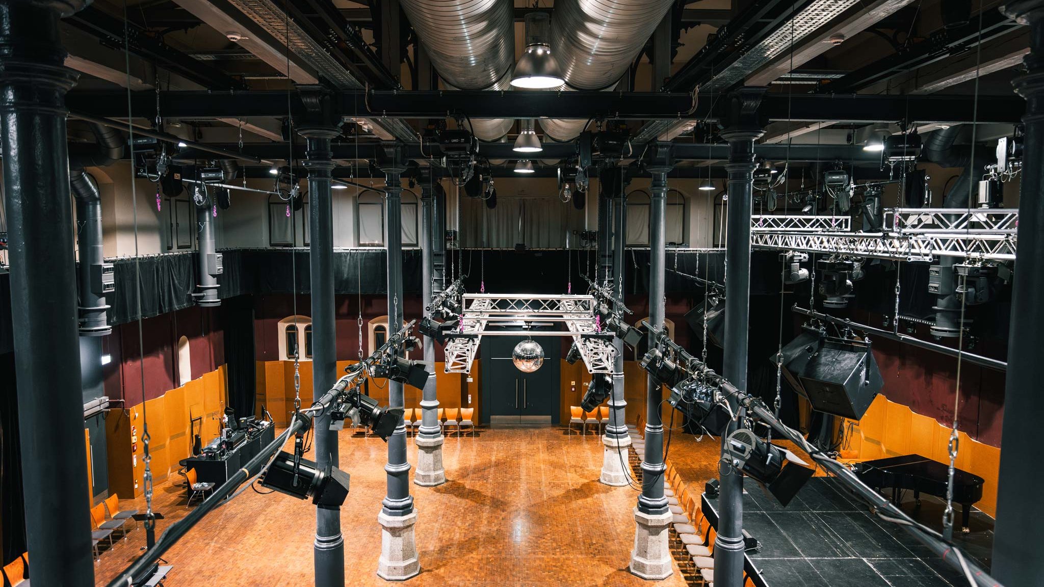 Großer Saal des Kulturforums Fürth mit gusseisernen Säulen, Beleuchtung, Bühne und Flügel.